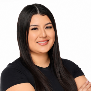 Portrait of a smiling woman with long dark hair, wearing a black shirt, arms crossed against a white background.